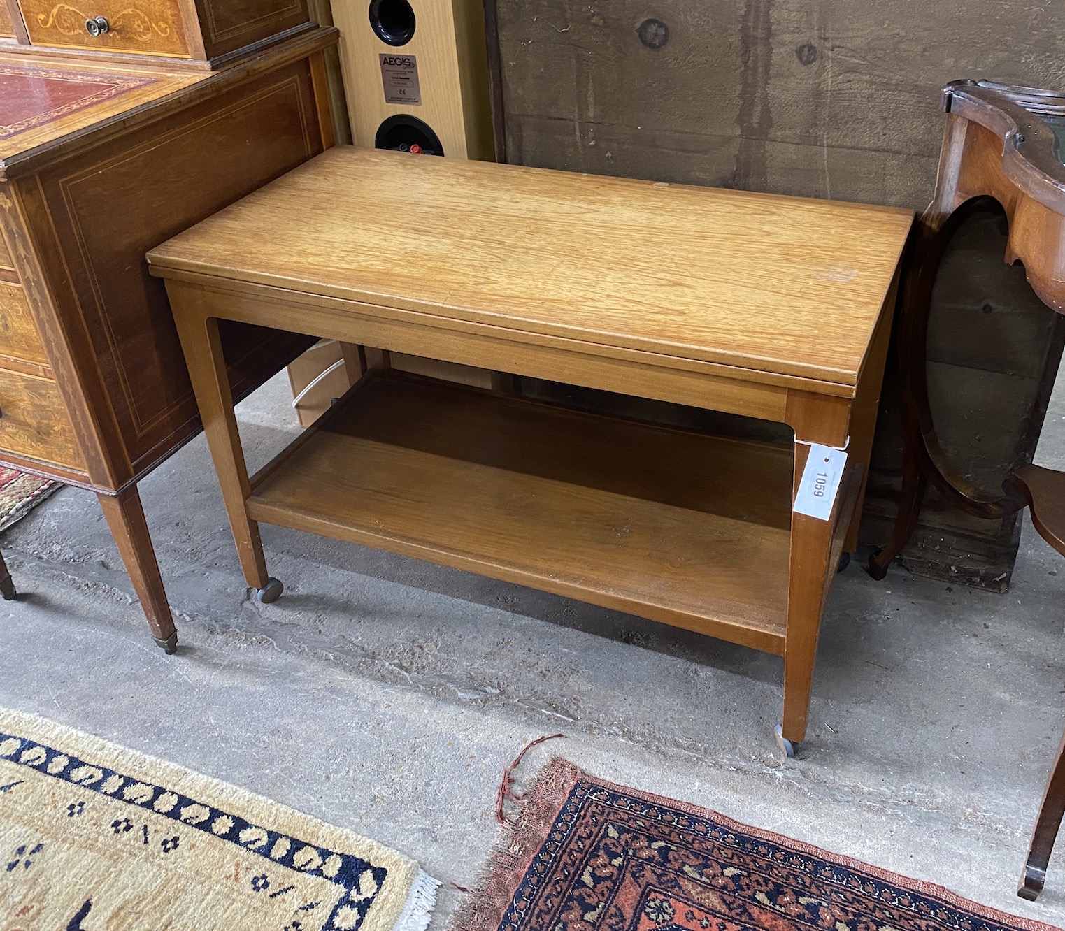 A mid century teak two tier table with hinged swivel top, width 83cm, depth 52cm, height 57cm